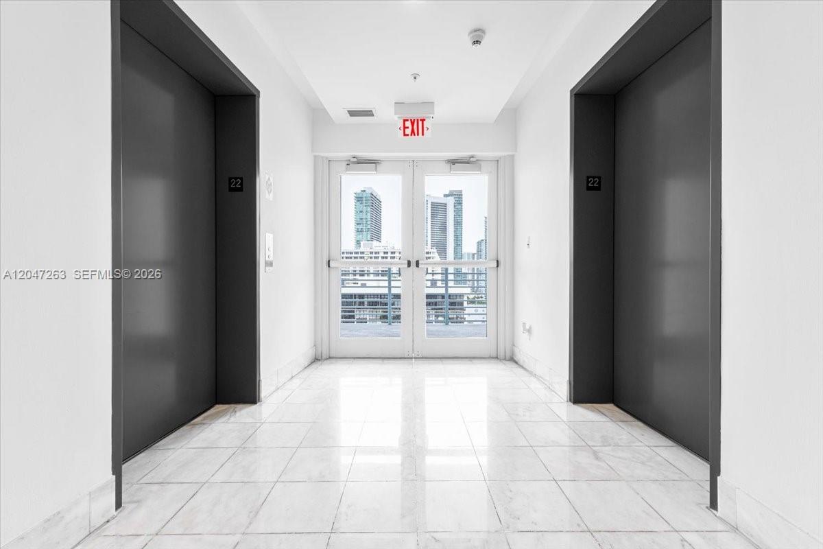 A hallway features white marble flooring, two dark elevator doors, and a glass exit door — 601 NE 36th St # 2203, Miami FL 33137, MIAMI, FL