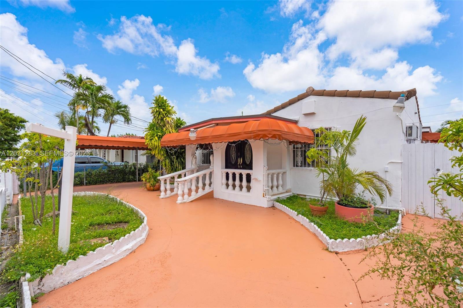 A white house with an orange awning, a curved driveway, and a small front porch — 615 SW 62nd Ct, Miami FL 33144, MIAMI, FL
