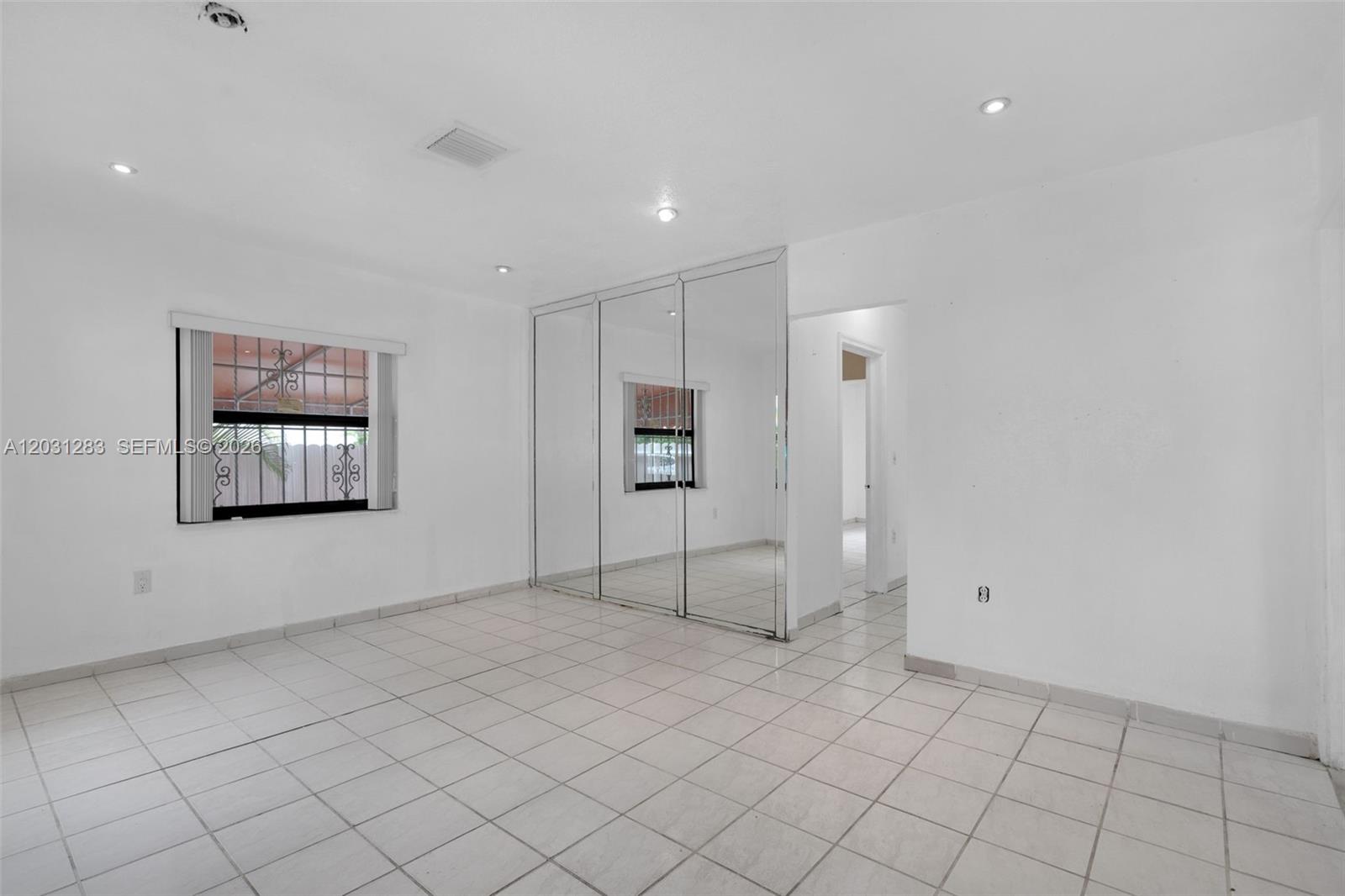 A bedroom with white walls, tiled flooring, recessed lighting, and mirrored closet doors — 615 SW 62nd Ct, Miami FL 33144, MIAMI, FL