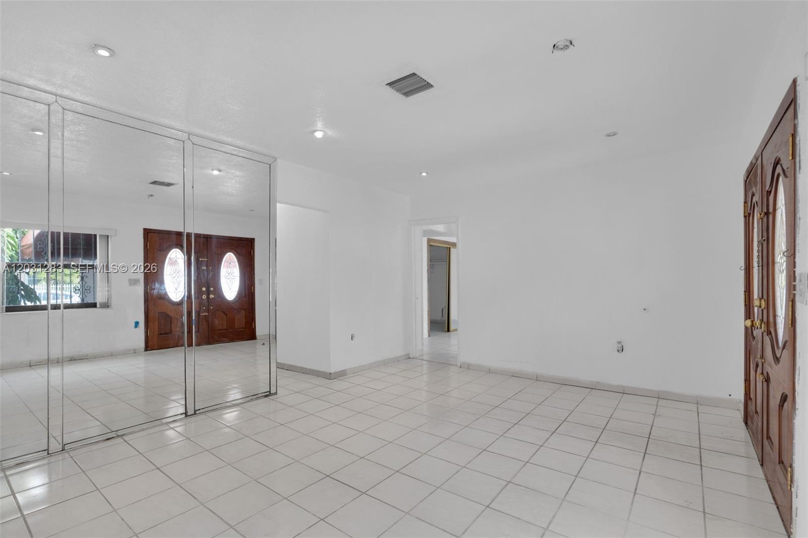 An empty room with white tile floors, white walls, and mirrored closet doors — 615 SW 62nd Ct, Miami FL 33144, MIAMI, FL