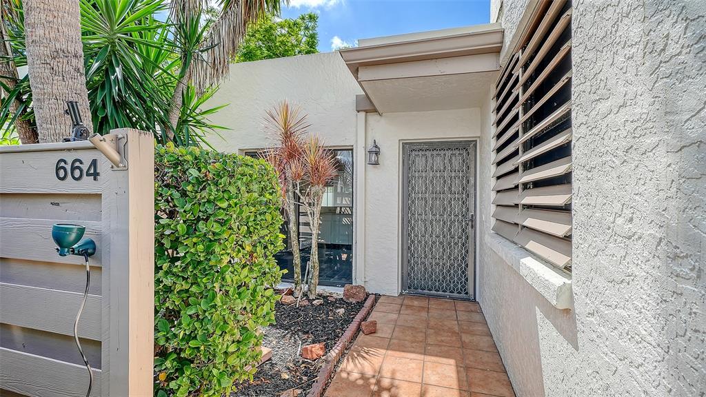 The exterior entrance features a tiled walkway, a screen door, and a privacy fence — 664 WOODLAWN DRIVE, BRADENTON, FL