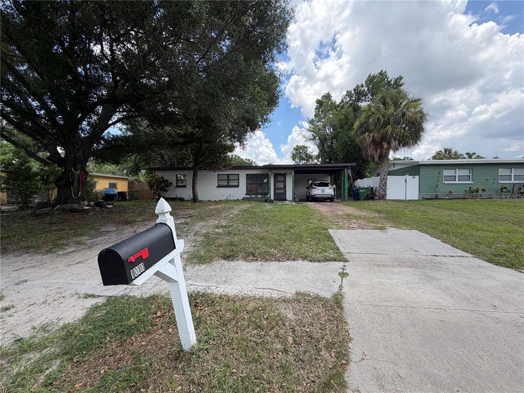 A single-story house with a carport and a mailbox in the foreground — 10111 N OLA AVENUE, TAMPA, FL