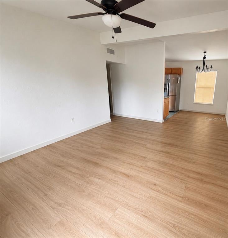 An open-concept living and dining area features light wood-look flooring and a ceiling fan — 10111 N OLA AVENUE, TAMPA, FL