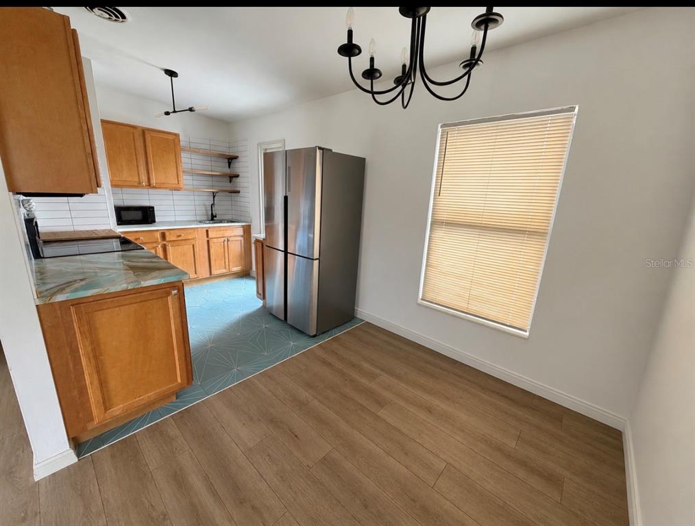 A kitchen with wood cabinets, blue patterned tile flooring, and a stainless steel refrigerator — 10111 N OLA AVENUE, TAMPA, FL