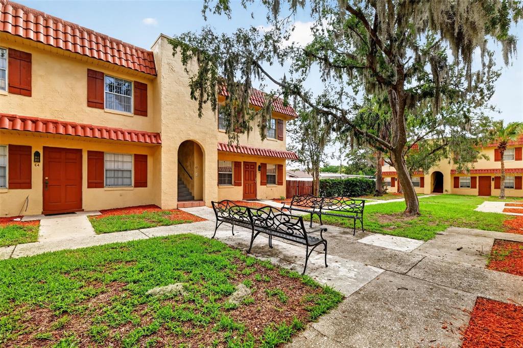 A two-story apartment building with stucco walls, red tile roofs, and outdoor benches — 1112 W MAIN STREET UNIT E7, LEESBURG, FL