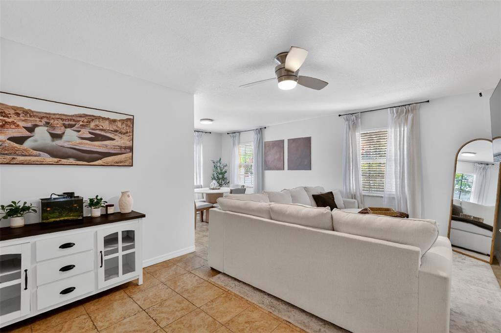 A living room with a white sectional sofa, tile flooring, and a white sideboard cabinet — 1112 W MAIN STREET UNIT E7, LEESBURG, FL