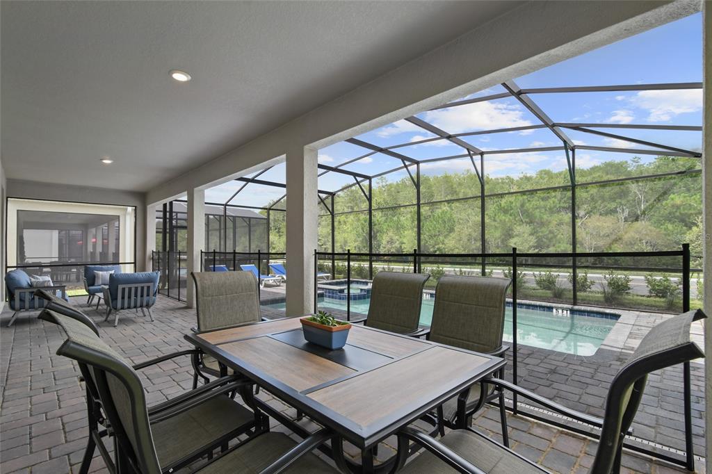 A covered patio features a dining set, pool, and spa enclosed by a screened lanai — 2726 OXYMORON WAY, KISSIMMEE, FL
