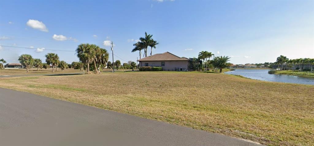 A vacant grassy lot sits next to a house and a small body of water — 17247 CARROWAY LANE, PUNTA GORDA, FL