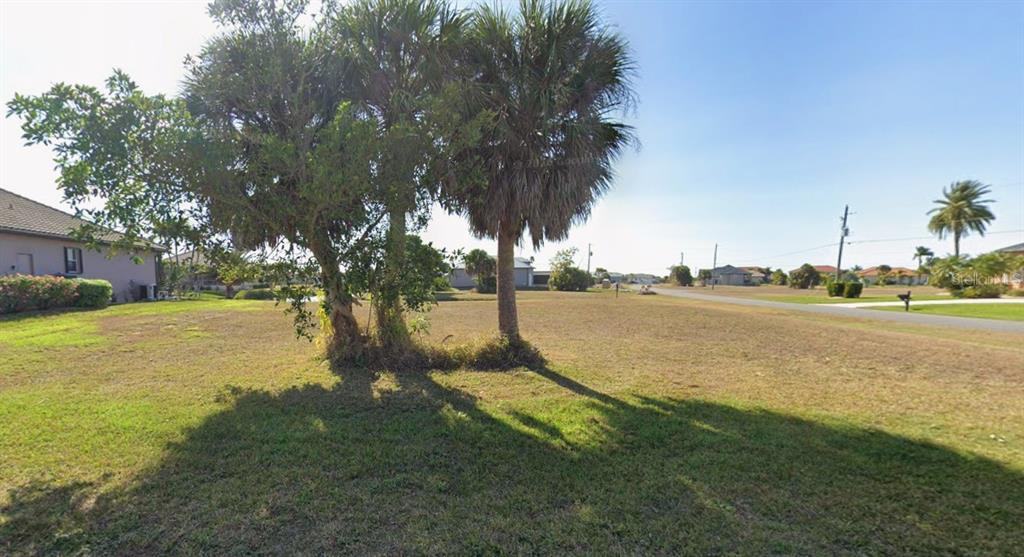 A vacant, grassy residential lot features several palm trees and a view of a paved road — 17247 CARROWAY LANE, PUNTA GORDA, FL