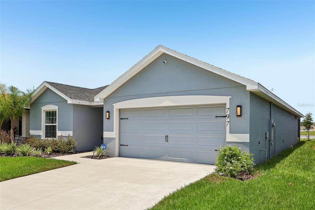 A single-story house with a grey stucco exterior, a two-car garage, and a concrete driveway — 797 CYPRESS CREEK RUN, ST CLOUD, FL