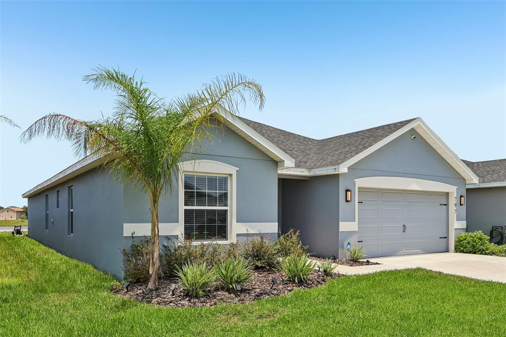 A single-story house with gray stucco siding, a two-car garage, and a front palm tree — 797 CYPRESS CREEK RUN, ST CLOUD, FL