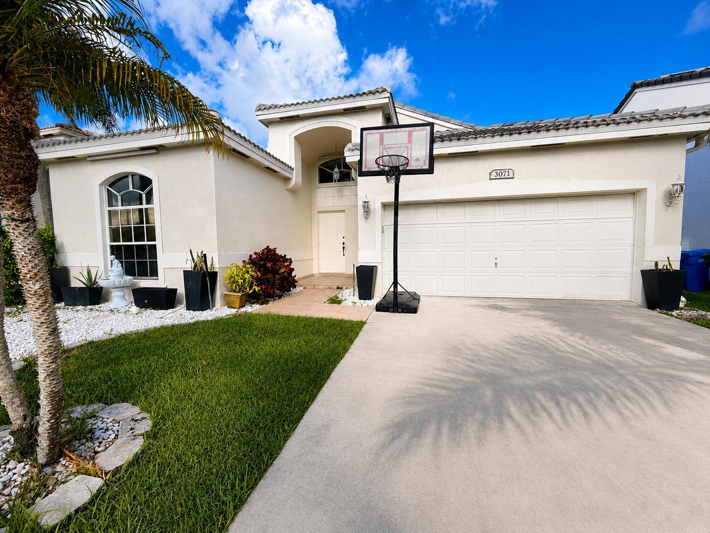 A single-story house with a white stucco exterior, a two-car garage, and a basketball hoop — 3071 Dogwood Lane, Margate FL 33063, MARGATE, FL