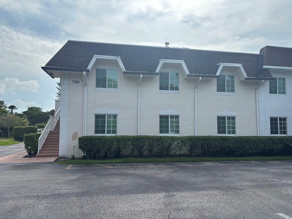 A two-story apartment building exterior with white stucco walls, a dark roof, and stairs — 700 SE 2nd Avenue # 409, Deerfield Beach FL 33441, DEERFIELD BEACH, FL