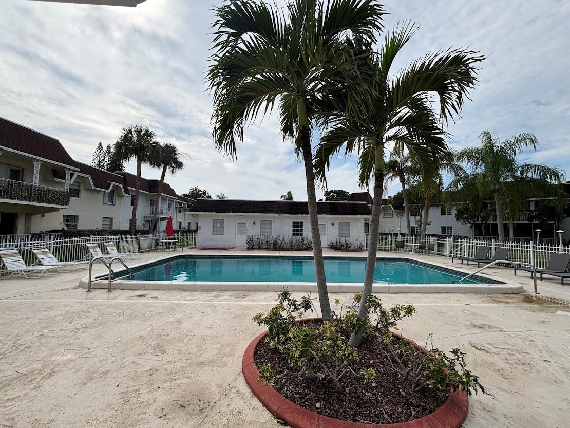 A rectangular swimming pool sits in a courtyard surrounded by palm trees and apartment buildings — 700 SE 2nd Avenue # 409, Deerfield Beach FL 33441, DEERFIELD BEACH, FL