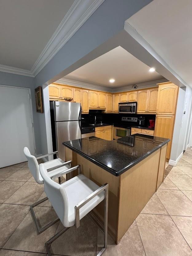A kitchen features light wood cabinets, black countertops, a stainless steel refrigerator, and two barstools — 700 SE 2nd Avenue # 409, Deerfield Beach FL 33441, DEERFIELD BEACH, FL