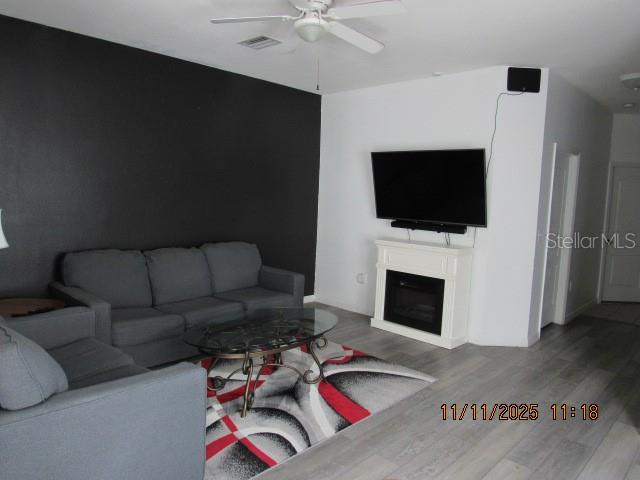 A living room features a dark accent wall, gray sofa, fireplace, and a patterned rug — 1944 GREENWOOD VALLEY DRIVE, PLANT CITY, FL