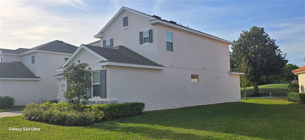 A two-story house with light-colored stucco siding, dark shutters, and a landscaped front yard — 18410 BLUE HERON CIRCLE, DEER ISLAND, FL