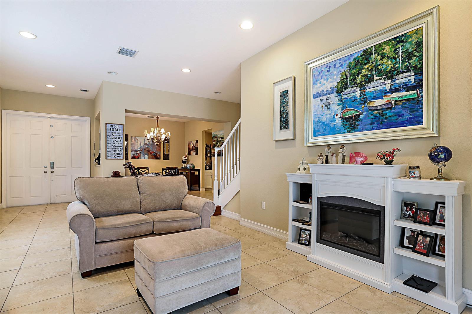 A living room features a beige sofa, a matching ottoman, and a white fireplace mantel — 7593 NW 113th Avenue, Parkland FL 33076, PARKLAND, FL