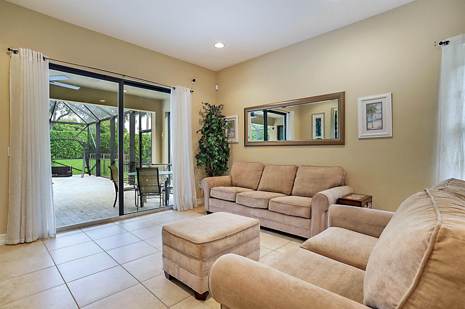 A living room with beige furniture, tile floors, and a sliding door to a patio — 7593 NW 113th Avenue, Parkland FL 33076, PARKLAND, FL