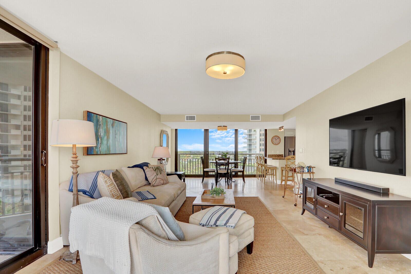 A living room features a beige sofa, a television, and a dining area with balcony views — 3000 N Ocean Drive # 7h, Singer Island FL 33404, SINGER ISLAND, FL