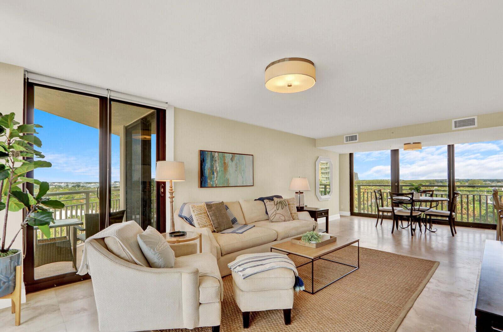A bright living room with beige furniture, a jute rug, and floor-to-ceiling windows overlooking greenery — 3000 N Ocean Drive # 7h, Singer Island FL 33404, SINGER ISLAND, FL