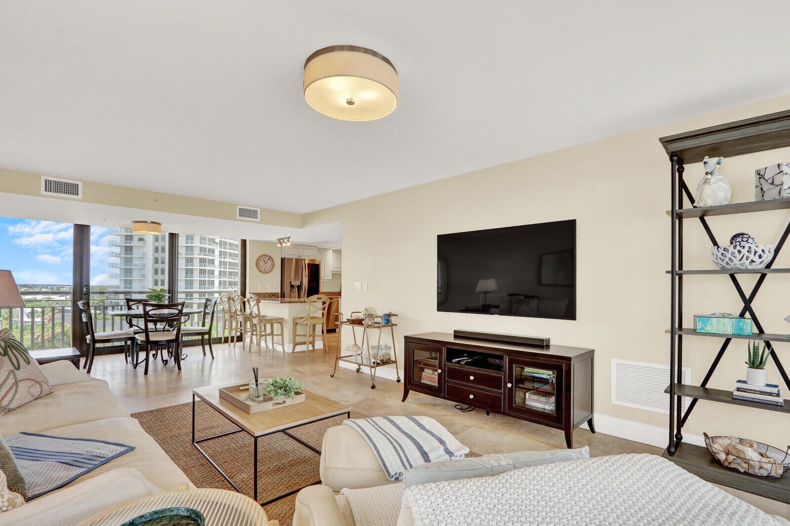 A living room features a television, dark wood media console, shelving unit, and dining area — 3000 N Ocean Drive # 7h, Singer Island FL 33404, SINGER ISLAND, FL