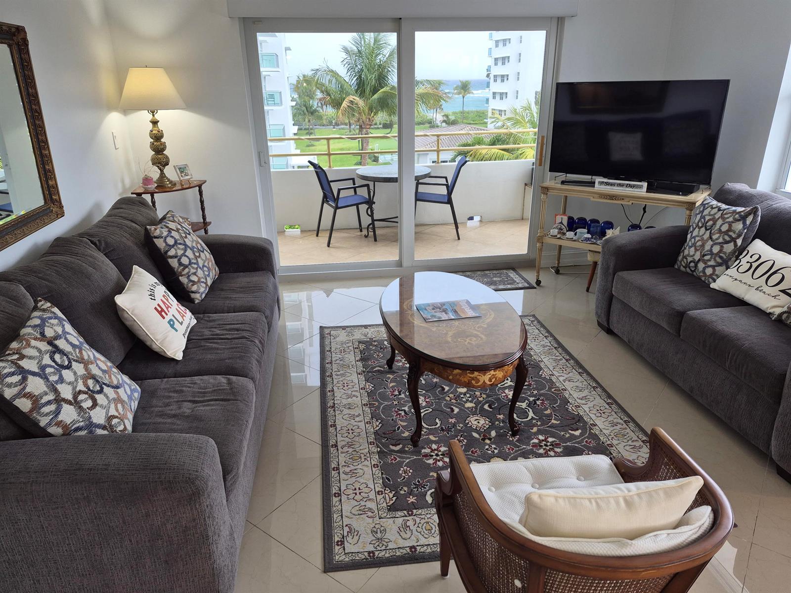 A living room with two grey sofas, a coffee table, and a balcony overlooking the ocean — 1630 N Ocean Boulevard # 314, Pompano Beach FL 33062, POMPANO BEACH, FL