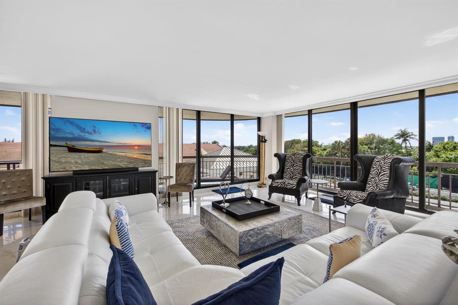 A living room features a white sectional sofa, zebra-print armchairs, and floor-to-ceiling windows — 4100 N Ocean Drive # 304, Riviera Beach FL 33404, RIVIERA BEACH, FL