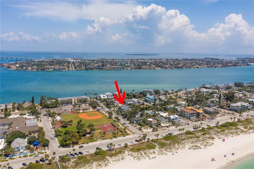 An aerial view shows a coastal neighborhood with a baseball field, beach, and water — 15TH AVENUE, ST PETE BEACH, FL