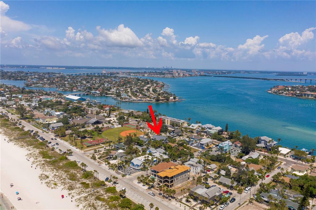 An aerial view shows a coastal neighborhood with a red arrow pointing toward a house — 15TH AVENUE, ST PETE BEACH, FL