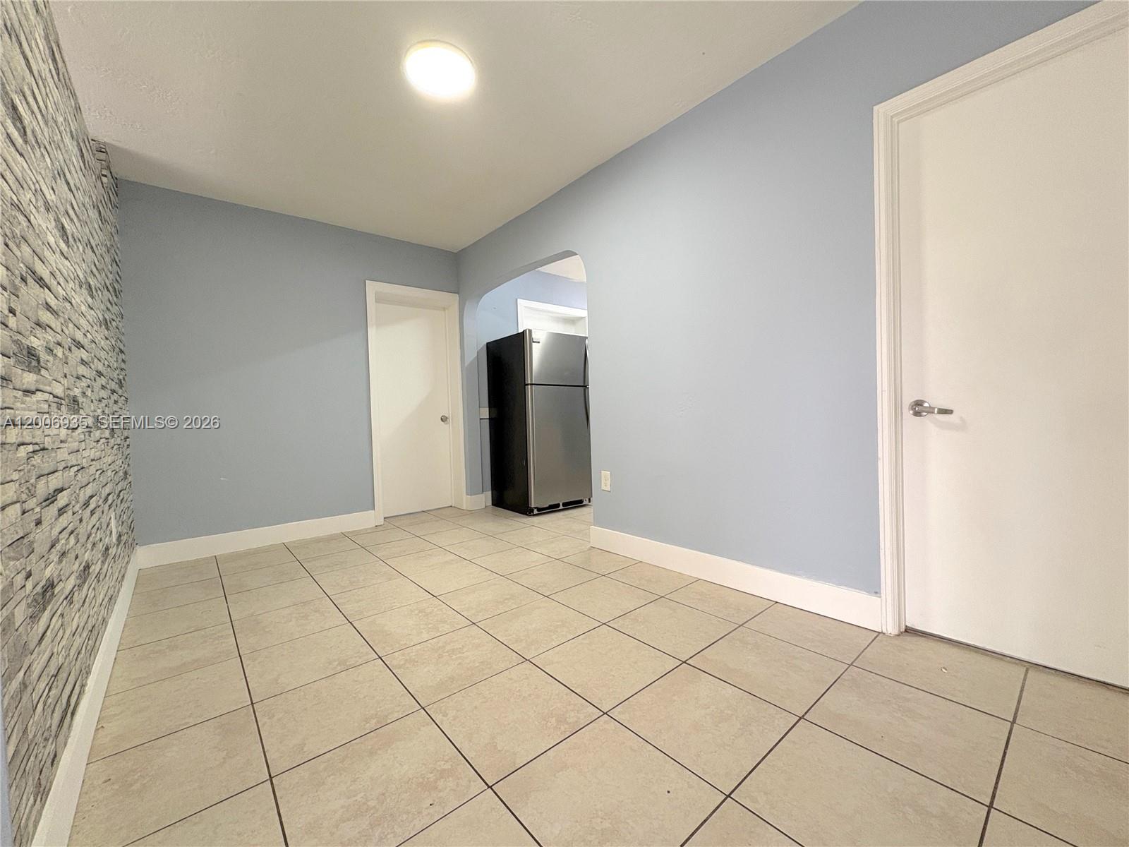 A room with light blue walls, tiled floors, and a stone-textured accent wall — 1815 Mckinley St # 9, Hollywood FL 33020, HOLLYWOOD, FL