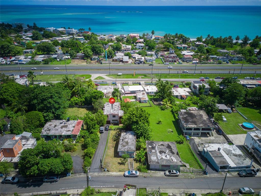 An aerial view shows a residential property with a red marker near a coastal highway — 10 FORTUNA 27 A, LUQUILLO, PR