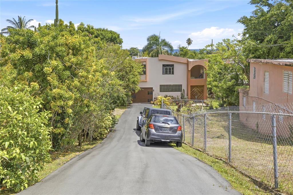 A paved driveway leads to a two-story house with a garage and a chain-link fence — 10 FORTUNA 27 A, LUQUILLO, PR