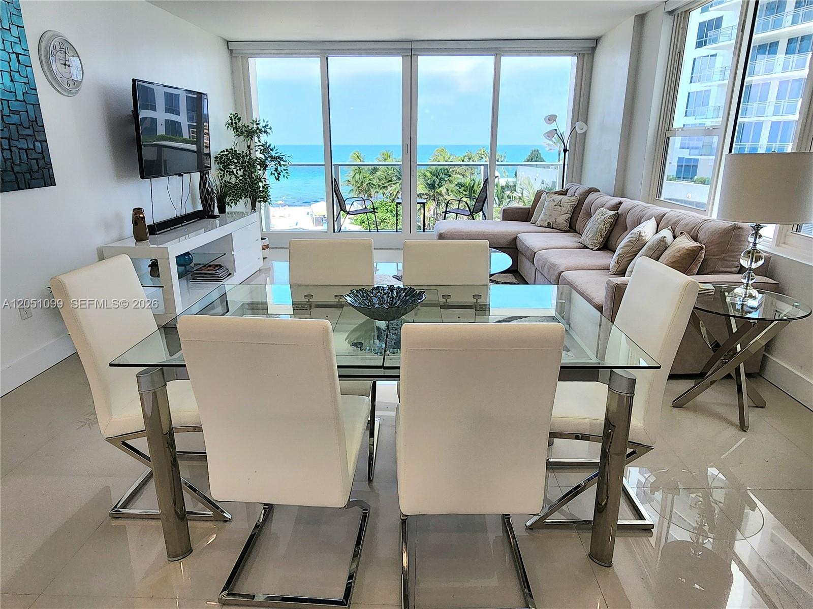 A dining area with a glass table and white chairs overlooks a balcony and ocean — 3505 S Ocean Dr # 521, Hollywood FL 33019, HOLLYWOOD, FL
