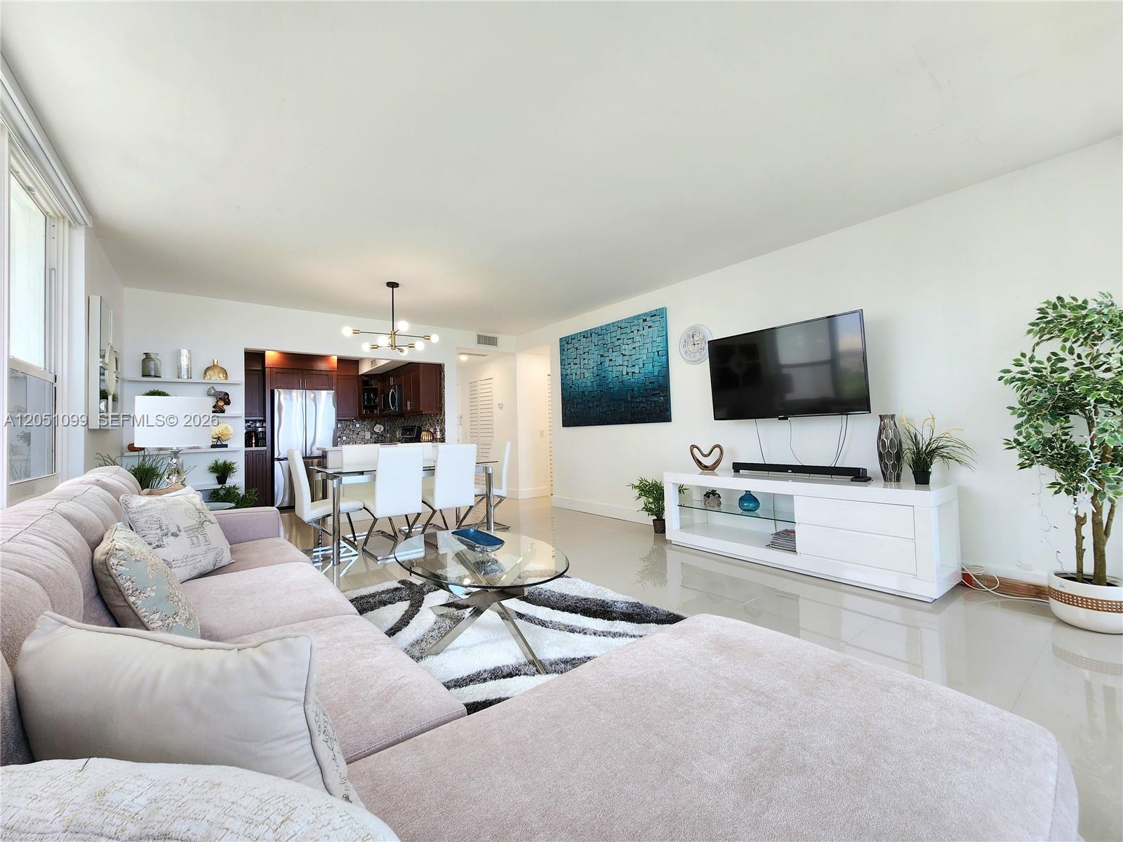 A living room features a sectional sofa, glass coffee table, dining area, and wall-mounted television — 3505 S Ocean Dr # 521, Hollywood FL 33019, HOLLYWOOD, FL
