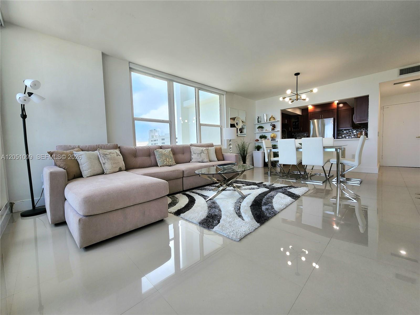 A modern open-plan living and dining area features a sectional sofa, glass-topped table, and tile flooring — 3505 S Ocean Dr # 521, Hollywood FL 33019, HOLLYWOOD, FL