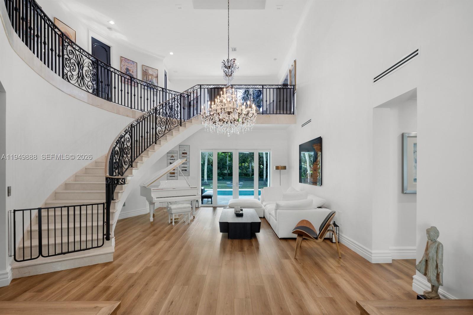 A grand foyer features a curved staircase, a white grand piano, and a crystal chandelier — 5002 SW 86th St, Miami FL 33143, MIAMI, FL