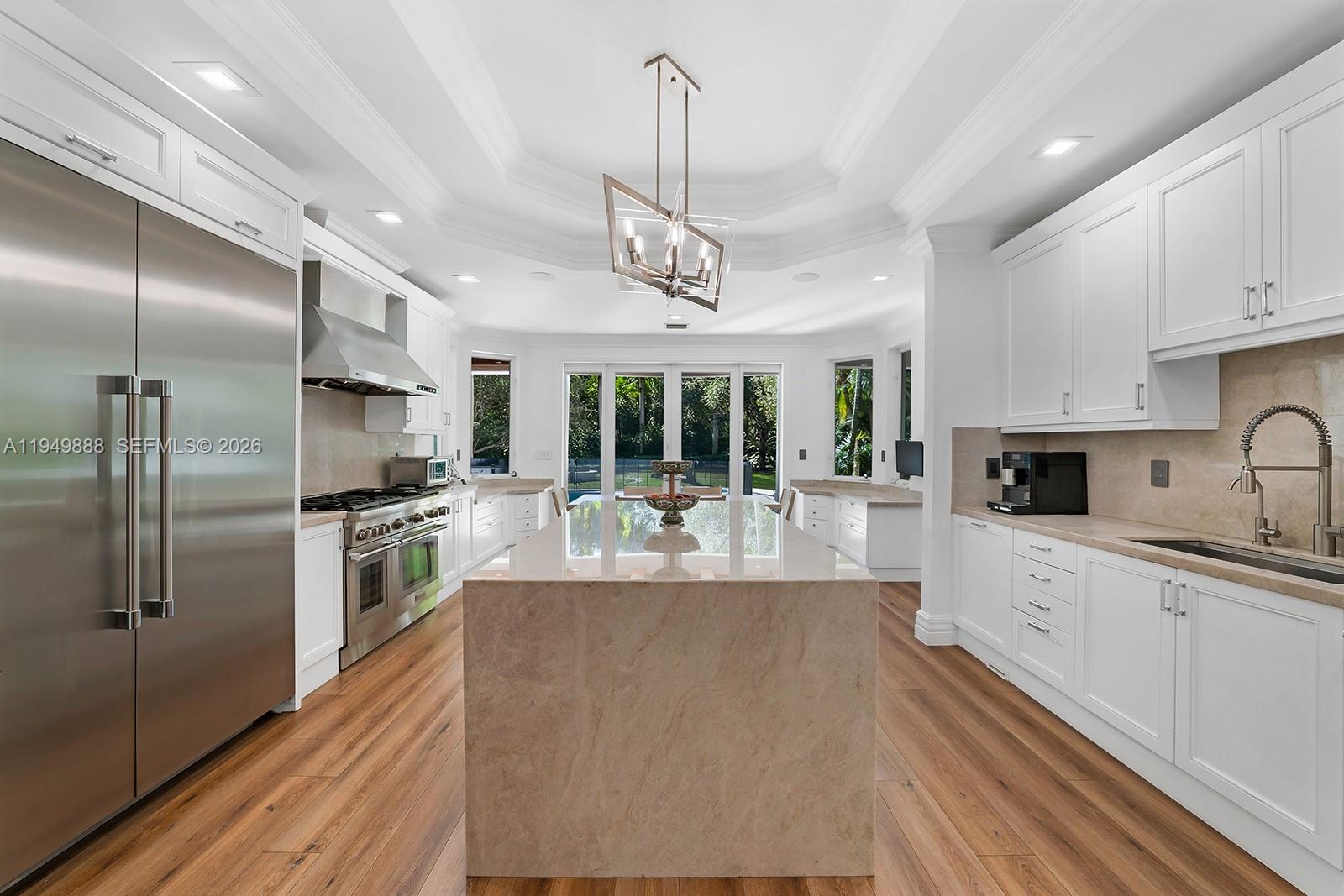 A bright kitchen features white cabinetry, a large stone island, and stainless steel appliances — 5002 SW 86th St, Miami FL 33143, MIAMI, FL