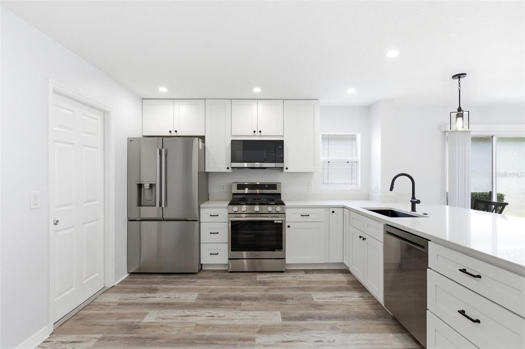 A modern kitchen features white cabinetry, stainless steel appliances, and a large island with seating — 1083 JACKSON STREET, THE VILLAGES, FL