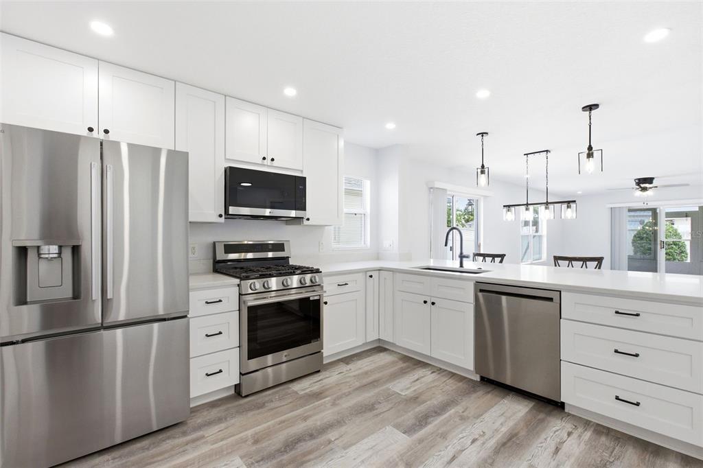 A modern kitchen features white cabinets, stainless steel appliances, and a large island with seating — 1083 JACKSON STREET, THE VILLAGES, FL