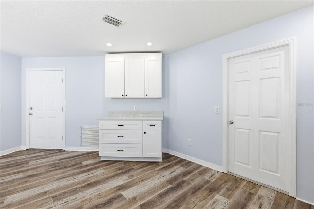 A room with light blue walls, wood-look flooring, and a white cabinet unit with countertops — 1083 JACKSON STREET, THE VILLAGES, FL