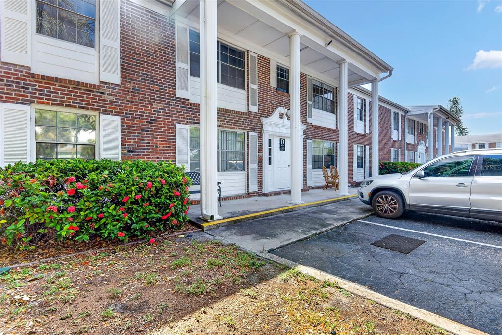 A white front door with a decorative pediment sits under a covered brick porch — 4507 9TH STREET W UNIT D6, BRADENTON, FL