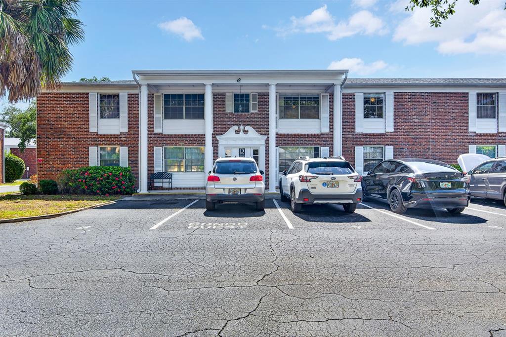 A virtually staged living room features light wood floors, a television, and neutral furniture — 4507 9TH STREET W UNIT D6, BRADENTON, FL