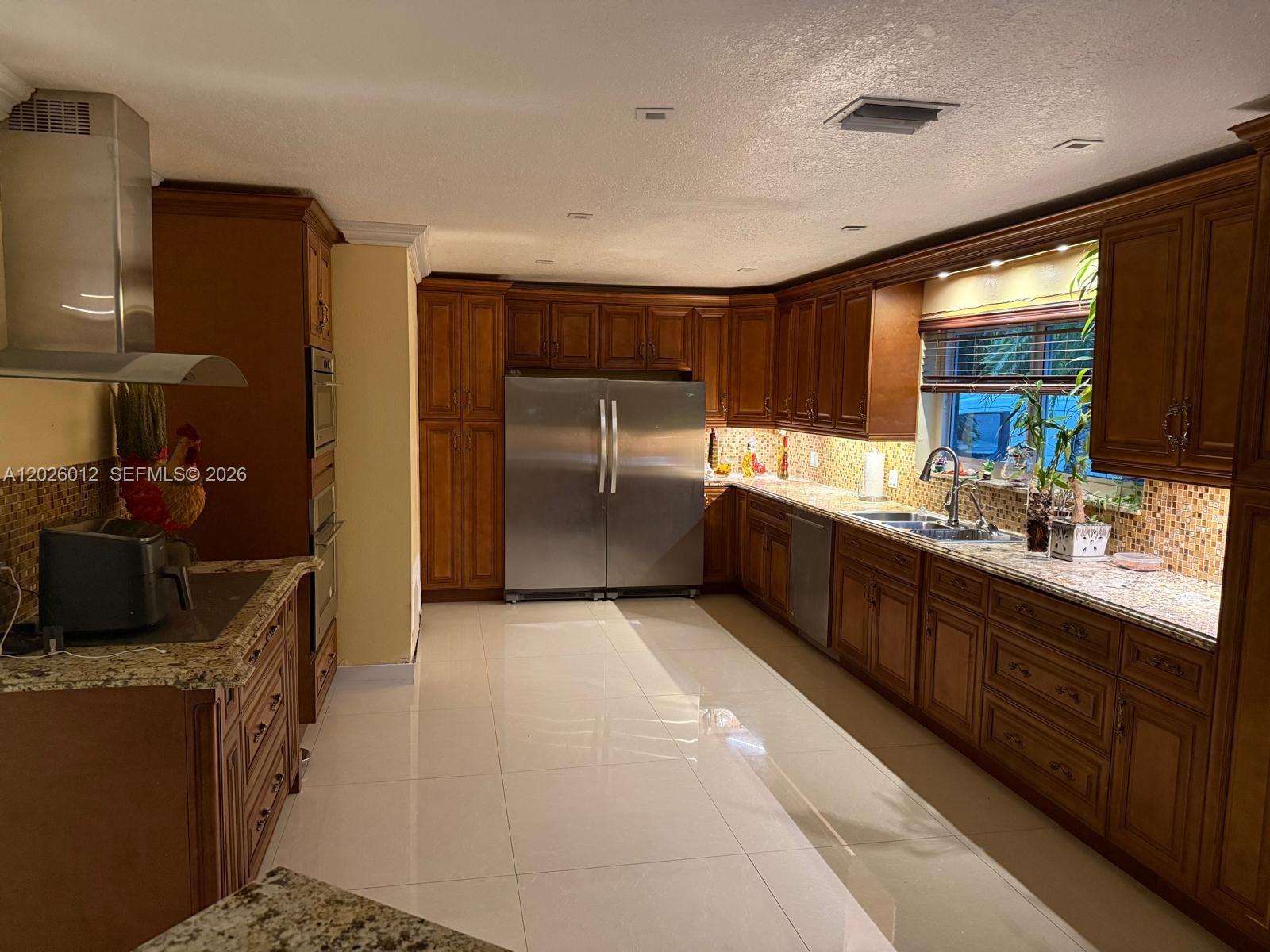 A kitchen features wood cabinets, granite countertops, stainless steel appliances, and light-colored tile flooring — 5540 SW 63rd Ct # 0, Miami FL 33155, MIAMI, FL