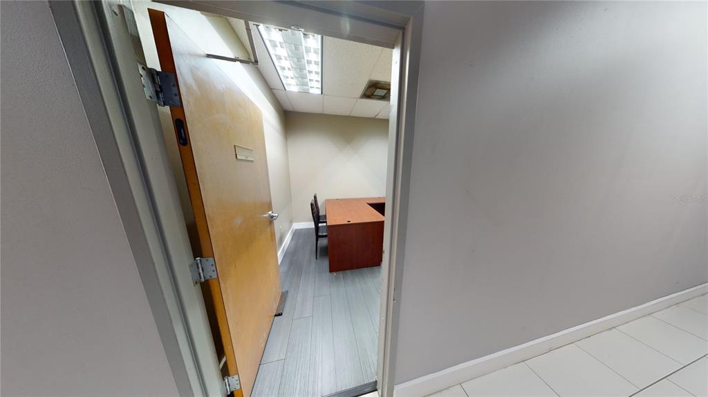An open door reveals a small office with a wood desk and gray flooring — 1576 TROPIC PARK DRIVE UNIT 1576, SANFORD, FL