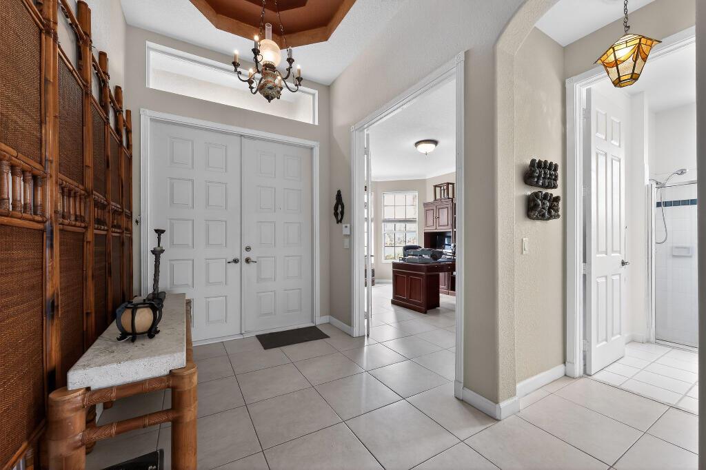A tiled entryway features a double front door, a chandelier, and an adjacent home office — 9430 Lantern Bay Circle, West Palm Beach FL 33411, WEST PALM BEACH, FL