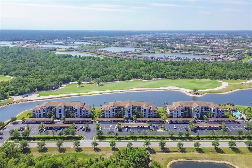 An aerial view shows three apartment buildings situated along a lake and a golf course — 17108 VARDON TERRACE UNIT 105, BRADENTON, FL