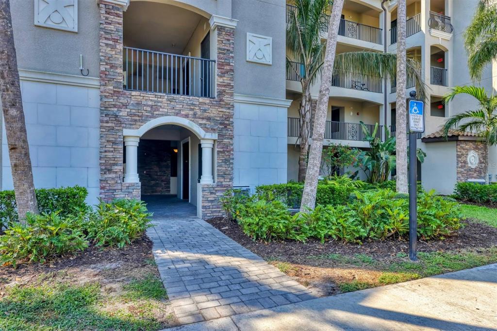 A stone-accented apartment building exterior features a covered entryway, a walkway, and palm trees — 17108 VARDON TERRACE UNIT 105, BRADENTON, FL