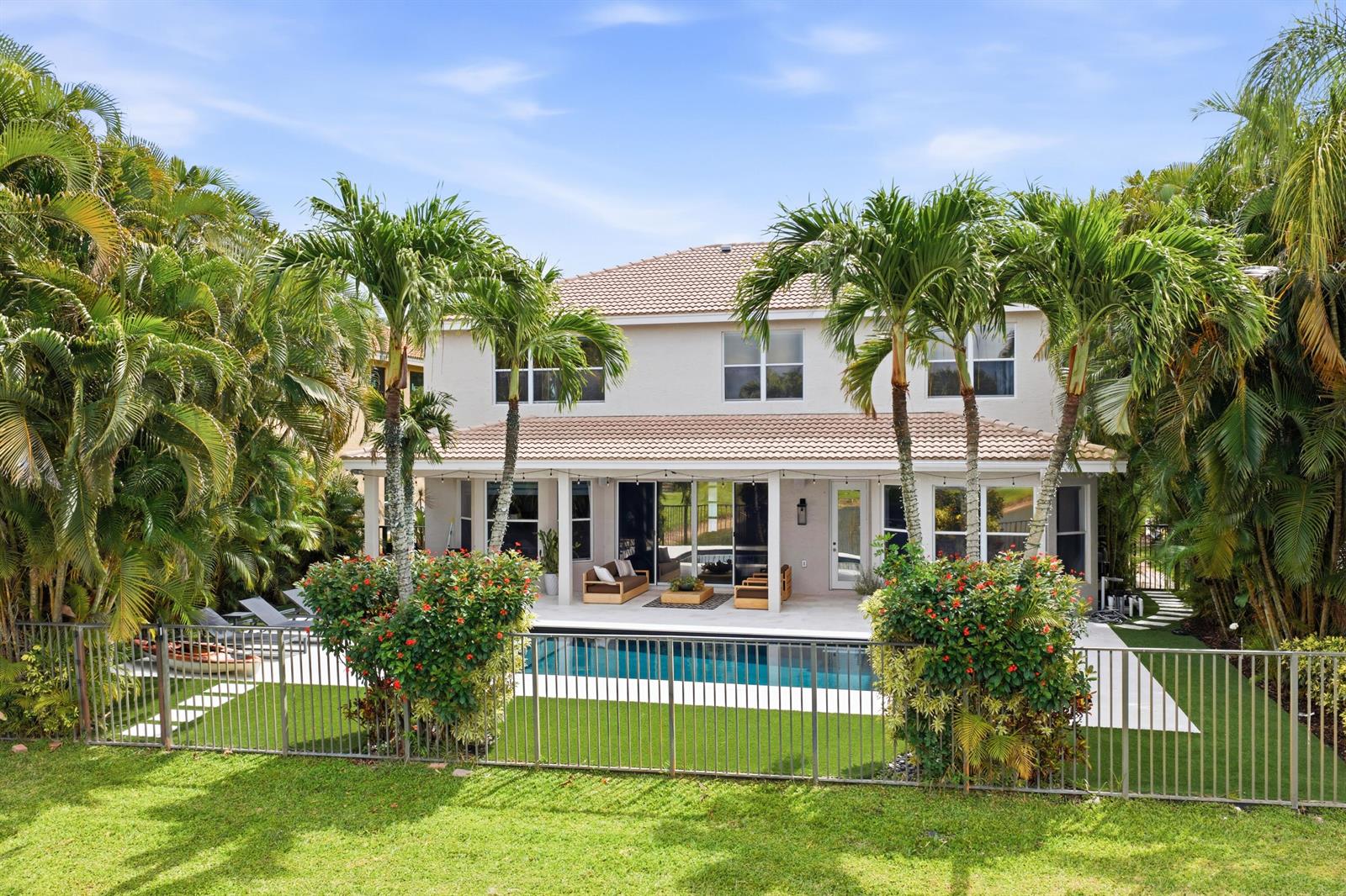A two-story house with a backyard pool, patio furniture, and surrounding palm trees — 19123 Two River Lane, Boca Raton FL 33498, BOCA RATON, FL