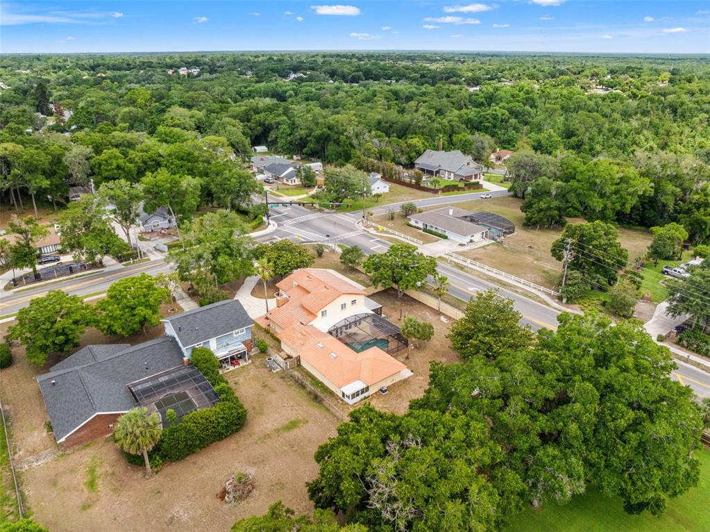 An aerial view shows two houses with swimming pools near a suburban road intersection — 1161 W LAKE BRANTLEY ROAD, ALTAMONTE SPRINGS, FL